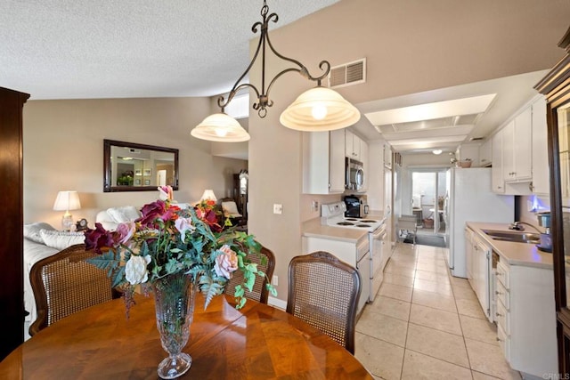 tiled dining area featuring vaulted ceiling, a textured ceiling, and sink