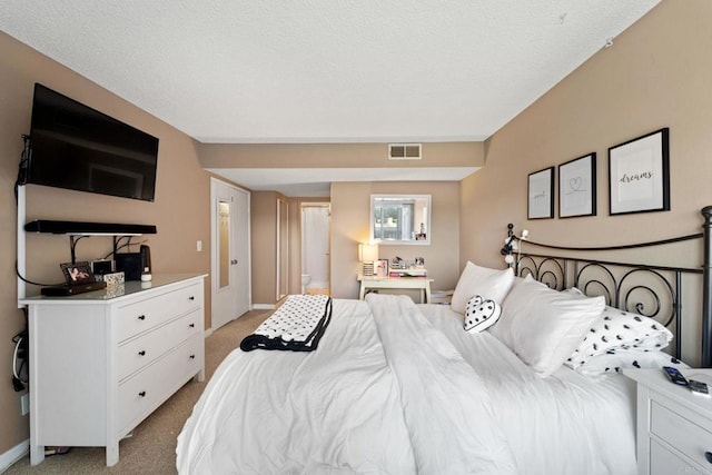 bedroom featuring a textured ceiling and light colored carpet