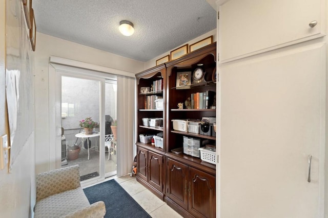 interior space with dark brown cabinets, a textured ceiling, and light tile patterned floors