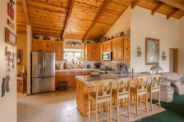 kitchen with beam ceiling, kitchen peninsula, stainless steel appliances, a kitchen bar, and high vaulted ceiling