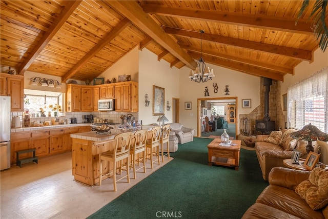 kitchen featuring tasteful backsplash, appliances with stainless steel finishes, a wood stove, kitchen peninsula, and tile counters