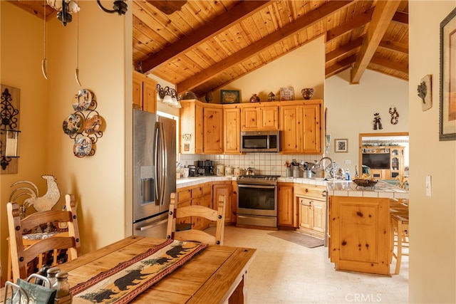 kitchen featuring light brown cabinets, tile countertops, beam ceiling, appliances with stainless steel finishes, and tasteful backsplash