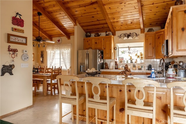 kitchen featuring kitchen peninsula, a healthy amount of sunlight, stainless steel appliances, and tasteful backsplash