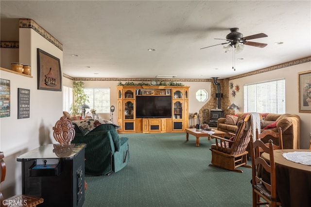 carpeted living room featuring ceiling fan, crown molding, and a wood stove