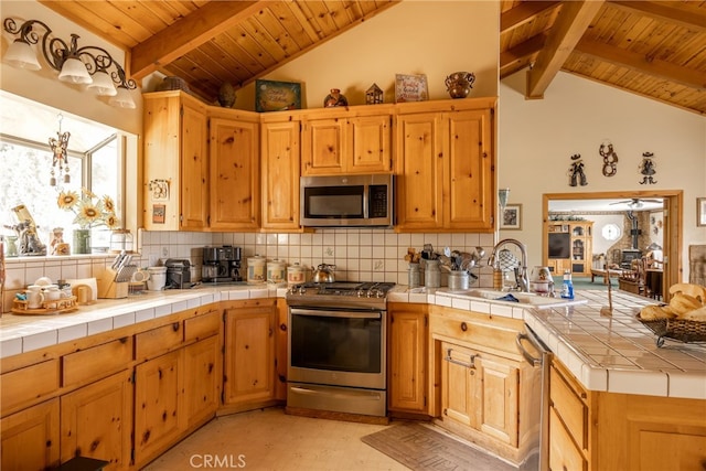 kitchen featuring decorative backsplash, lofted ceiling with beams, stainless steel appliances, and tile counters