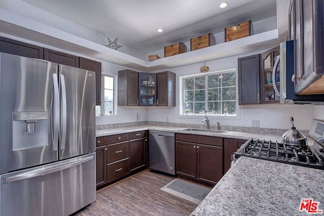 kitchen with dark brown cabinets, sink, light stone countertops, appliances with stainless steel finishes, and dark hardwood / wood-style flooring