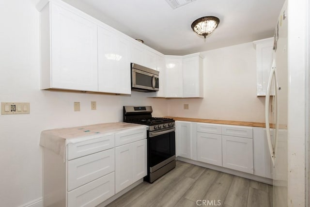 kitchen with white cabinets, stainless steel appliances, and light wood-type flooring