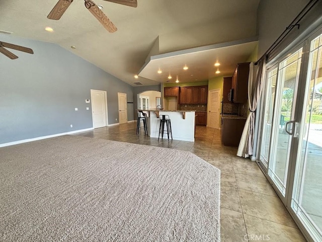 interior space with ceiling fan, a breakfast bar, a kitchen island, and lofted ceiling