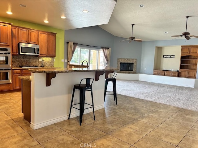 kitchen with a breakfast bar, light tile patterned floors, stainless steel appliances, and vaulted ceiling