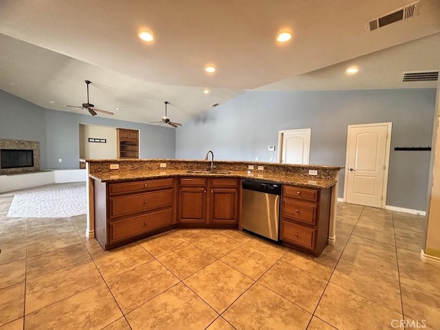 kitchen featuring sink, stainless steel dishwasher, dark stone countertops, vaulted ceiling, and a kitchen island with sink