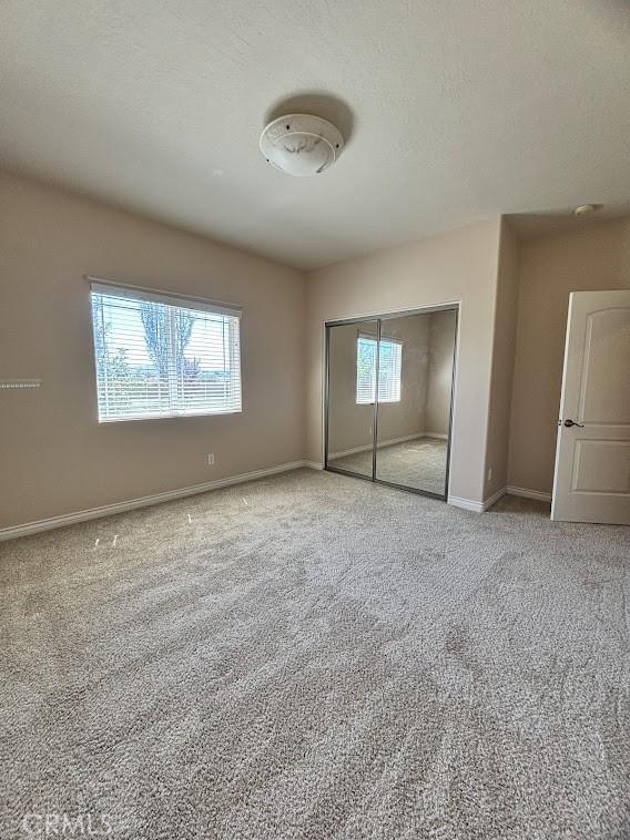 unfurnished bedroom featuring a closet, carpet floors, and a textured ceiling