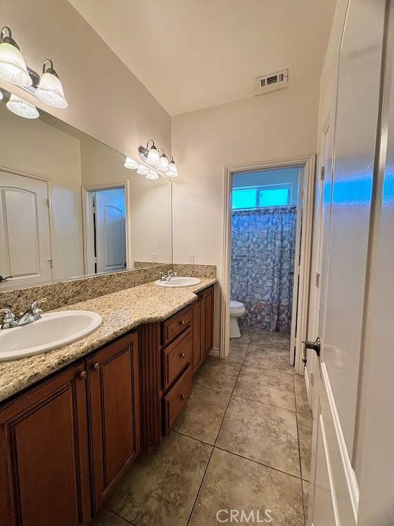 bathroom with tile patterned floors, vanity, toilet, and walk in shower