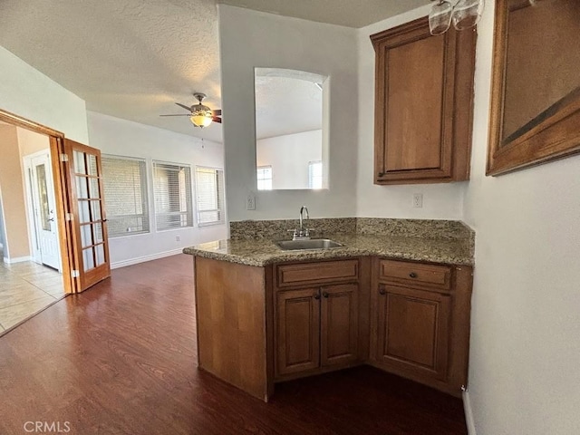 kitchen featuring sink, ceiling fan, a textured ceiling, stone countertops, and dark hardwood / wood-style flooring