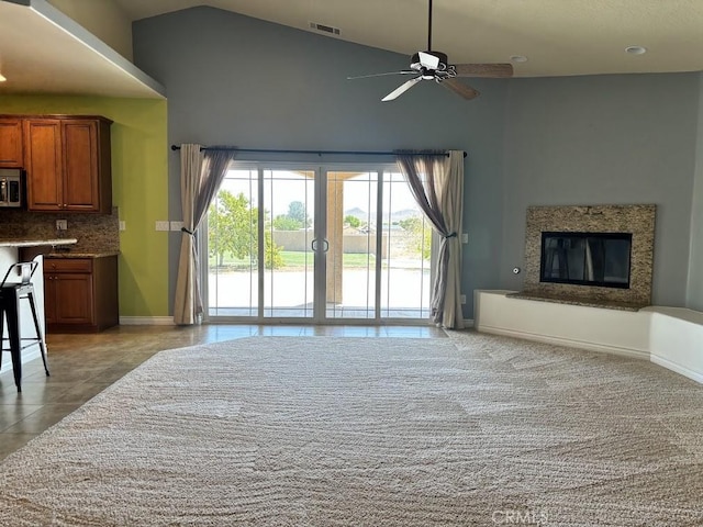 unfurnished living room featuring ceiling fan, light tile patterned floors, and high vaulted ceiling