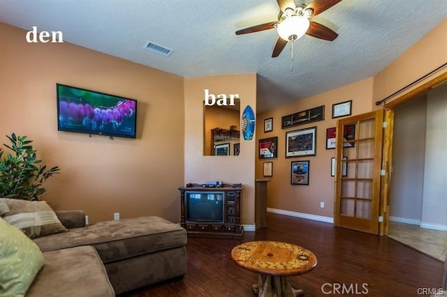 living room featuring dark hardwood / wood-style floors, ceiling fan, and a textured ceiling