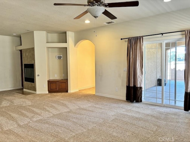 unfurnished living room featuring light carpet, ceiling fan, and a textured ceiling