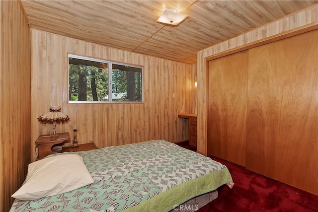 bedroom with wooden ceiling, wooden walls, dark carpet, and a closet