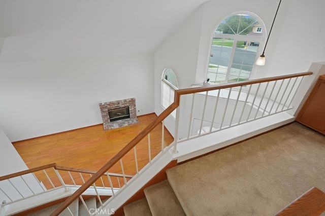 stairway featuring hardwood / wood-style floors and a brick fireplace