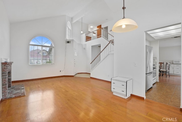 unfurnished living room with a high ceiling, a fireplace, and hardwood / wood-style floors