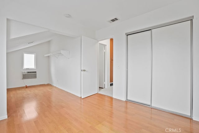 bonus room featuring light wood-type flooring, lofted ceiling, and a wall mounted air conditioner