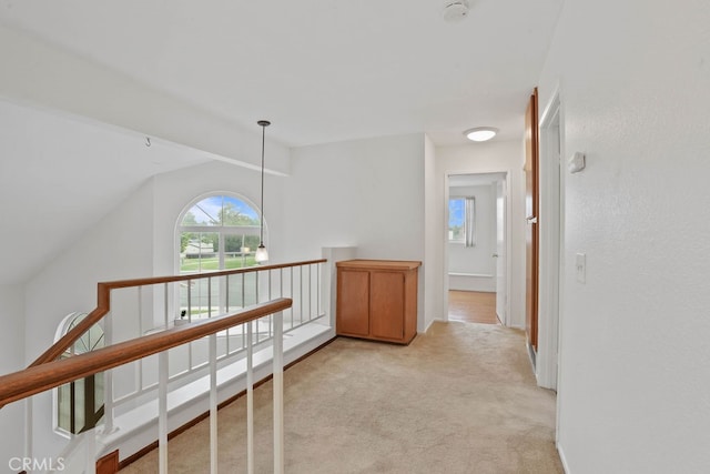 hall with vaulted ceiling and light colored carpet