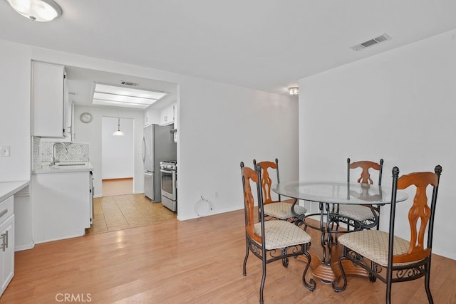 dining space featuring light wood-type flooring and sink