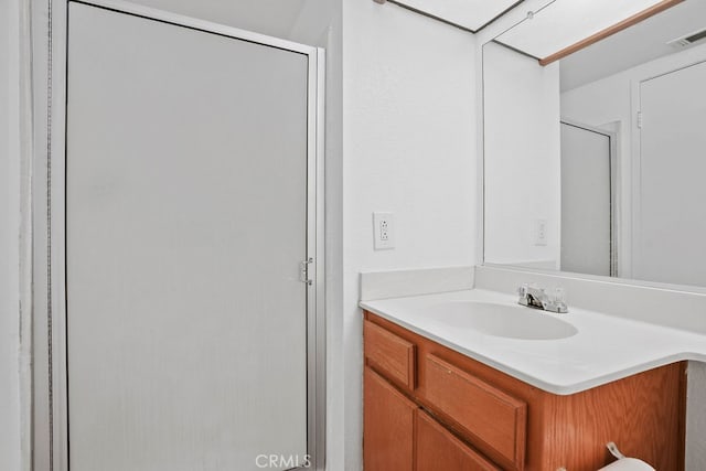 bathroom with a shower with shower door and vanity