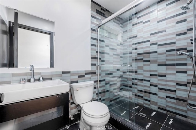 bathroom with vanity, a shower with door, tile walls, tile patterned flooring, and toilet