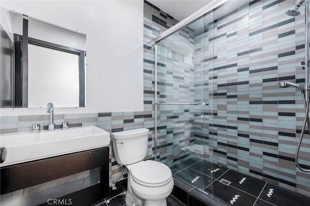 bathroom with vanity, a shower with shower door, tile walls, and toilet