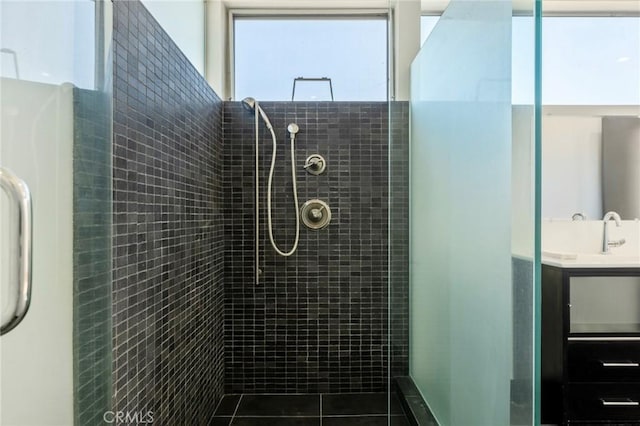 bathroom featuring tile patterned floors, a tile shower, and sink