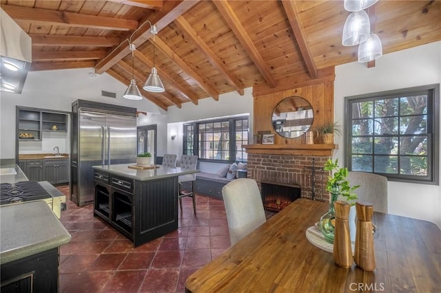 kitchen featuring beam ceiling, hanging light fixtures, built in refrigerator, a fireplace, and a kitchen island