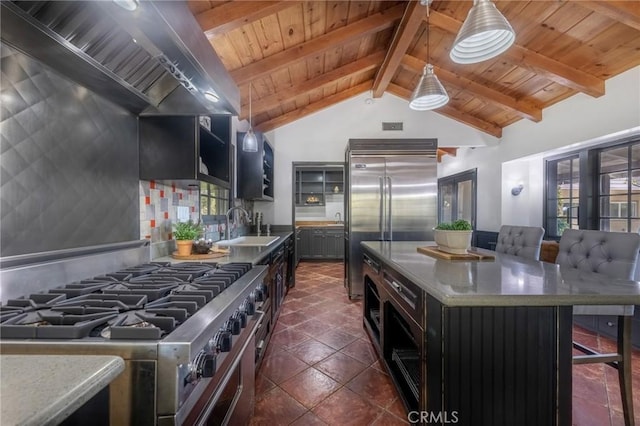 kitchen featuring sink, wall chimney exhaust hood, premium appliances, vaulted ceiling with beams, and pendant lighting