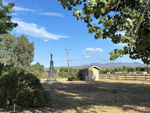 view of yard with a mountain view, a rural view, and a storage shed