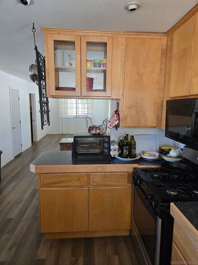 kitchen with stainless steel range with gas stovetop, light brown cabinetry, dark wood-type flooring, and kitchen peninsula