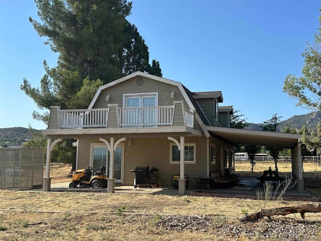 back of property featuring a balcony, a mountain view, and a carport