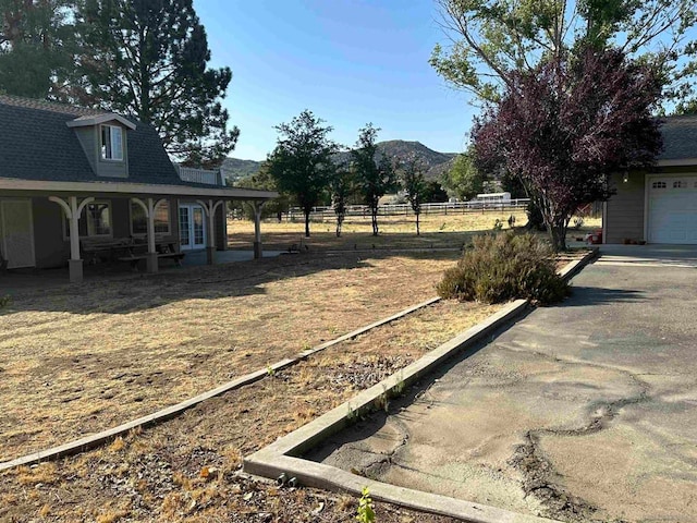 view of yard with a garage, a mountain view, and a porch