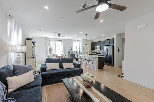 living room featuring light hardwood / wood-style flooring and ceiling fan