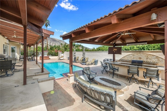 view of swimming pool with grilling area, an outdoor kitchen, a mountain view, a gazebo, and a patio