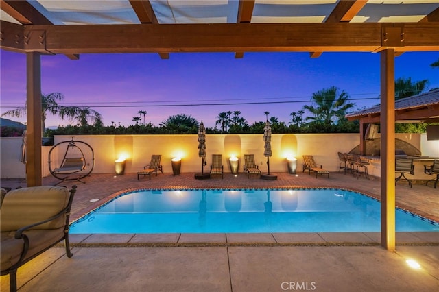 pool at dusk featuring a patio