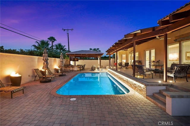 pool at dusk featuring a gazebo and a patio