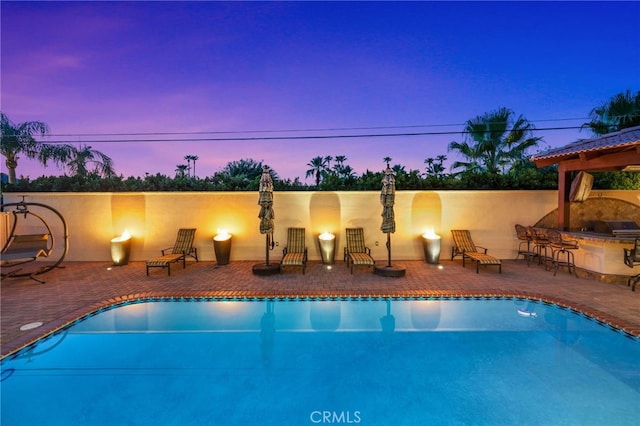 pool at dusk featuring a patio area