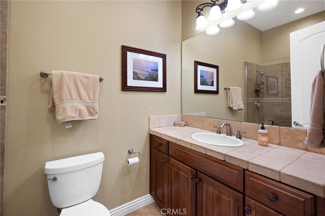 bathroom featuring vanity, a tile shower, toilet, and tile patterned floors