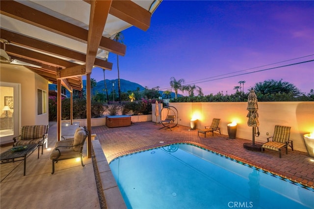 pool at dusk featuring a patio area and a mountain view