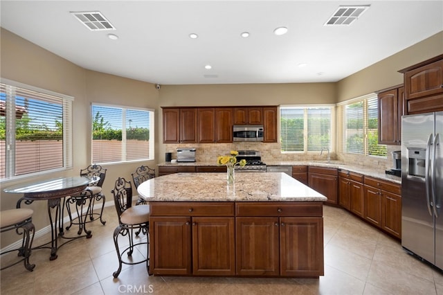 kitchen with a wealth of natural light, a kitchen island, and stainless steel appliances