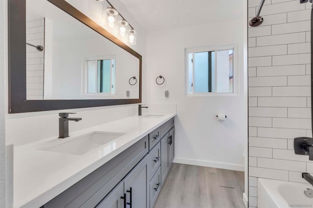 bathroom featuring dual bowl vanity, tiled shower / bath combo, and wood-type flooring