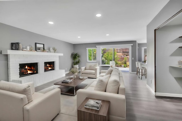 living room with a brick fireplace and light hardwood / wood-style floors