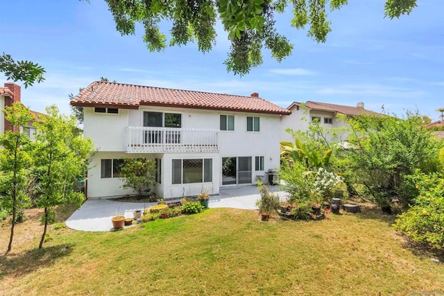 rear view of house with a patio, a yard, and a balcony