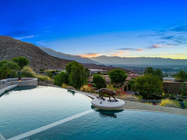 pool at dusk featuring a mountain view