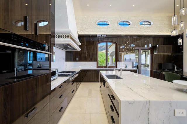 kitchen featuring backsplash, sink, hanging light fixtures, light stone counters, and stainless steel appliances