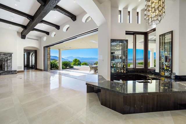 bar featuring a towering ceiling, a mountain view, plenty of natural light, and beamed ceiling